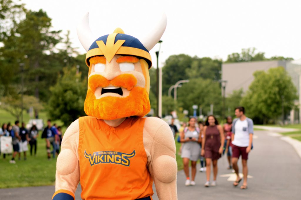 Chester walking on campus with students in background